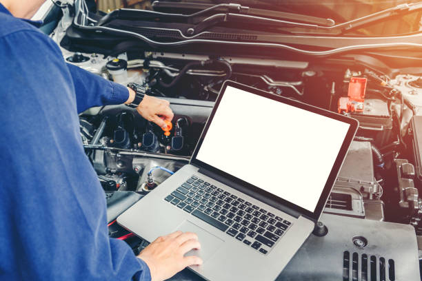istock Professional car mechanic working in auto repair service using laptop on car 870391414