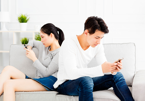 Couple sitting on couch and watching their phones