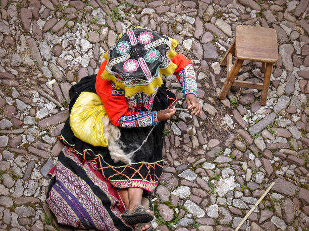 vista dall'alto della donna peruviana in abito etnico tradizionale che gira lana di alpaca - art tribal art traditional culture multi colored foto e immagini stock
