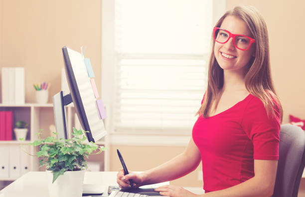 istock Young woman working with a pen tablet in her home office 870402426