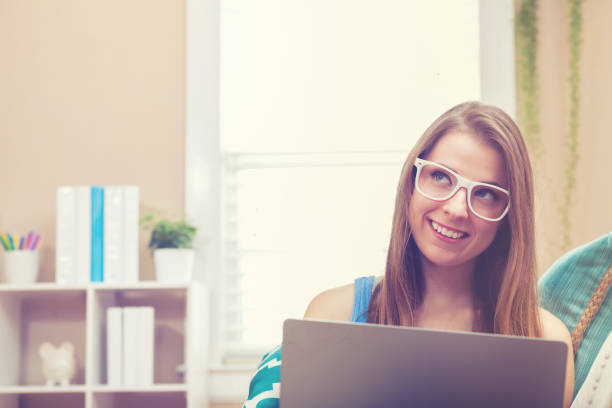 istock Young woman using her laptop on her couch 870402454
