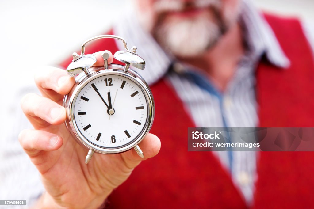 closeup of man in red vest holding a clock closeup of man with beard and red vest holding a clock Adult Stock Photo