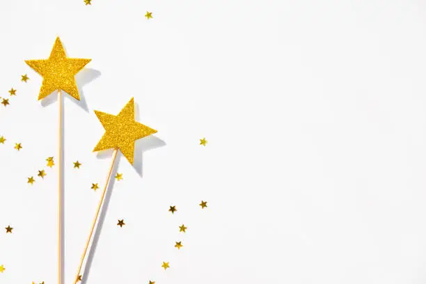 Two golden party magic wands and sequins on a white background. Copy space.
