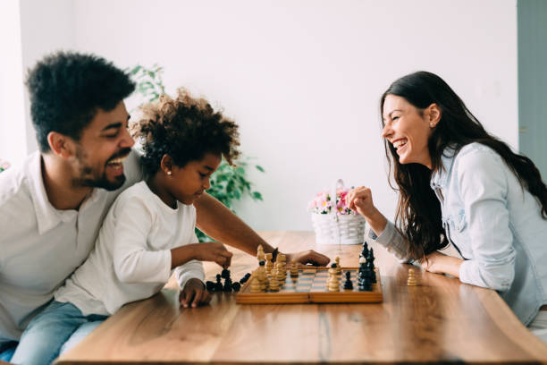 Happy family playing chess together at home Happy family playing chess together at their home chess house stock pictures, royalty-free photos & images