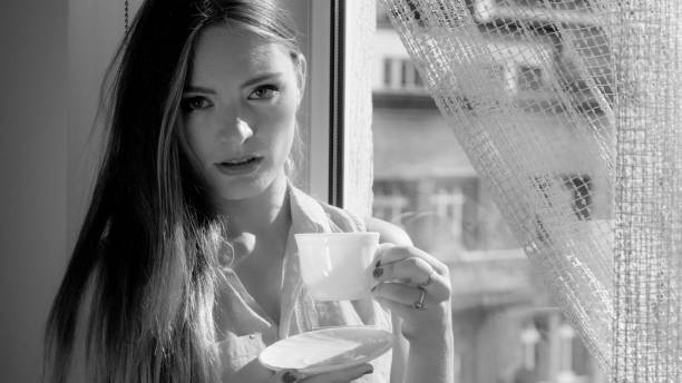 istock Woman looking through window, relaxing drinking coffee 870411952