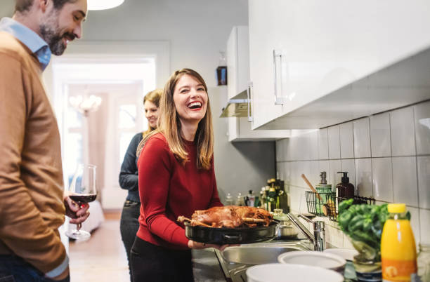 young woman smiling and holding christmas poultry in kitchen young woman smiling  and holding christmas poultry in kitchen celebrity roast stock pictures, royalty-free photos & images