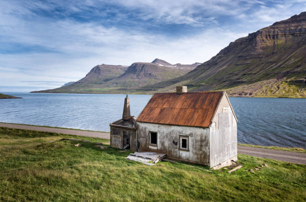Abandoned fjord-land house with a bright red roof in Seydisfjordur, Eastern Iceland