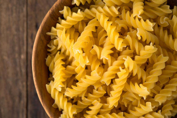 istock raw pasta in wood plate on wood background 870419518