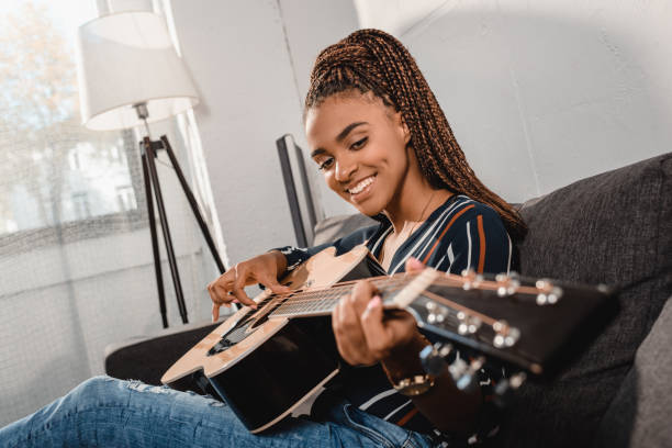 istock woman playing guitar on couch 870423410