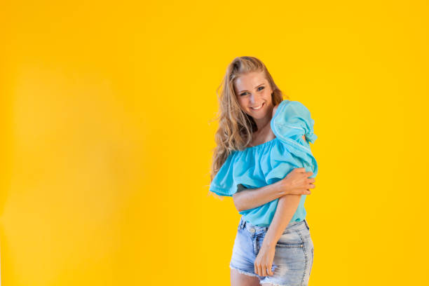 istock blonde girl in a blue dress, on a yellow background 870423708