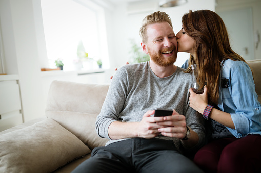 Romantic young couple expressing their love by kissing and smiling