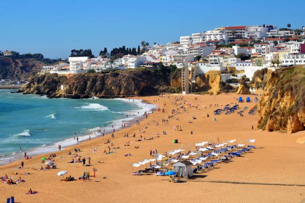 Albufeira beach, Algarve, Portugal - town, cliffs and Praia dos Pescadores and Praia do Peneco Albufeira, Algarve, Portugal: the town develops above the ocean-front cliffs by the beaches known as  Praia dos Pescadores and Praia do Peneco - many people on the beaches, none a central subject of the image albufeira photos stock pictures, royalty-free photos & images