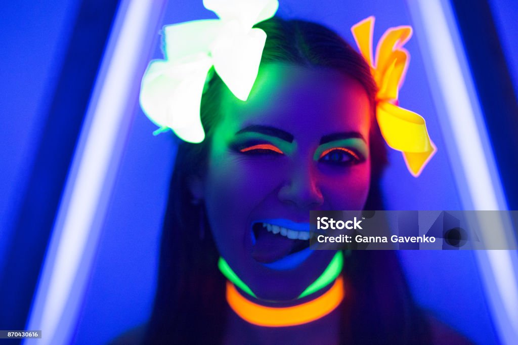 neon make up Creative woman model shine blue green orange colors. Bright conceptual art make-up glows under ultraviolet light. Club disco neon party time. Drink alcohol feel wild energy of music. Halloween horror Adult Stock Photo