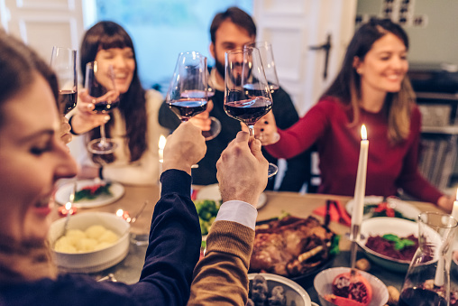 friends clinking wine glasses at christmas table