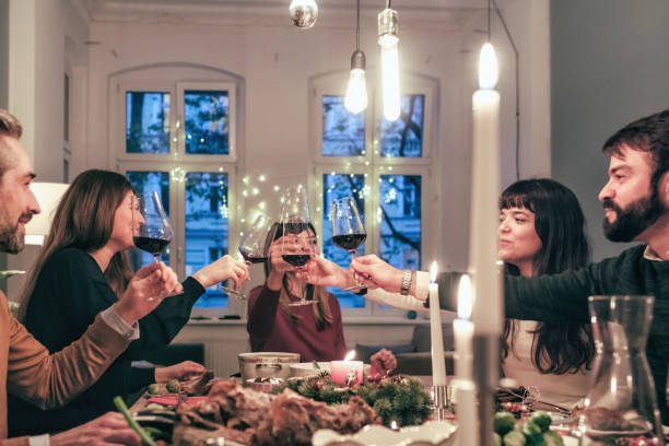 istock friends clinking wine glasses at illuminated christmas table 870437828