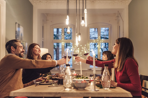 happy friends clinking wine glasses at christmas table