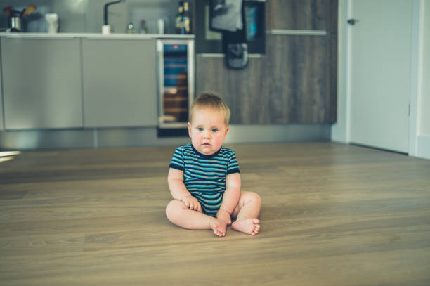 istock Little baby sitting on the floor in kitchen 870445358