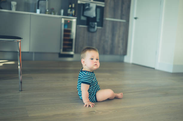 istock Little baby sitting on the floor in kitchen 870445426