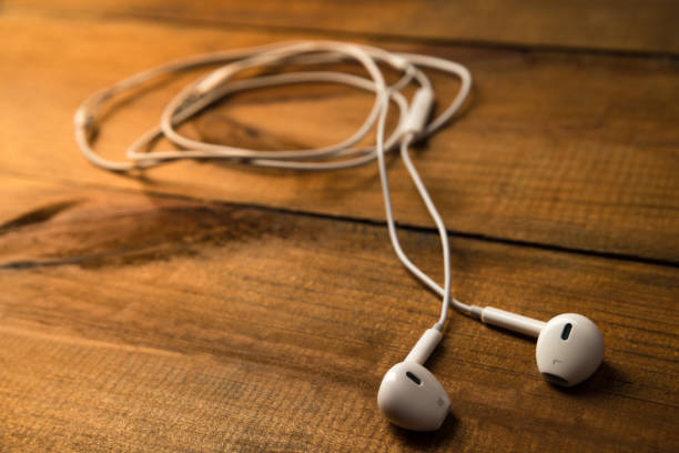 istock White little headphones on a wooden isolated background. Horizontal frame 870450086
