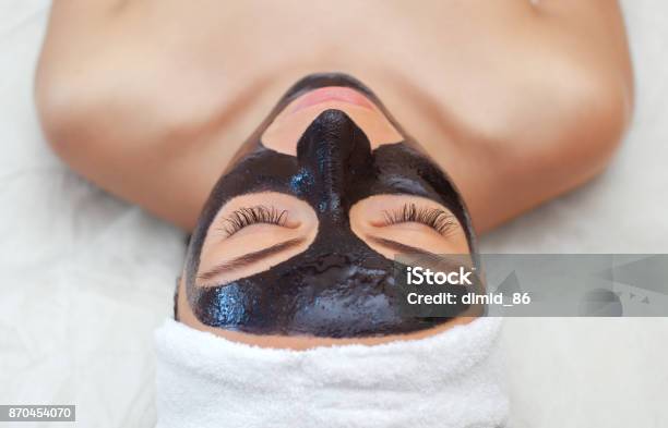 The Procedure For Applying A Black Mask To The Face Of A Beautiful Woman Stock Photo - Download Image Now