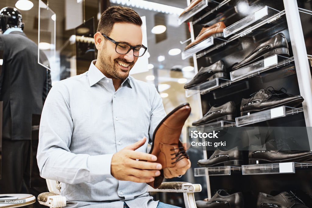 Man enjoying shopping Portrait of handsome young man buying clothes in the store. Shoe Stock Photo