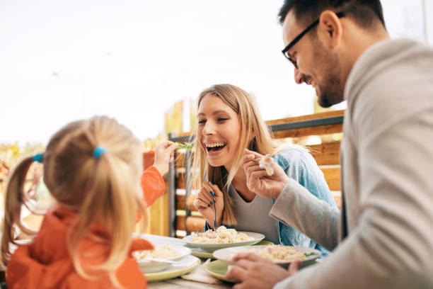 Family enjoying restaurant Young parents dining in a restaurant with four years old adorable girl. kids eating noodles stock pictures, royalty-free photos & images