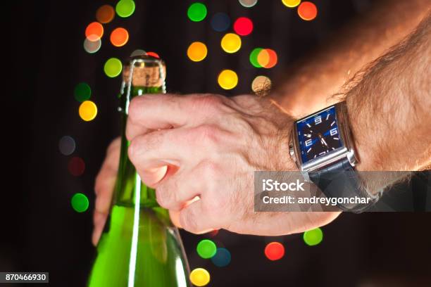 Opening A Bottle Of Sparkling Wine Like Champagne A Mans Hand With A Watch New Years Lights Happy New Year And Christmas Celebration 2018 Stock Photo - Download Image Now