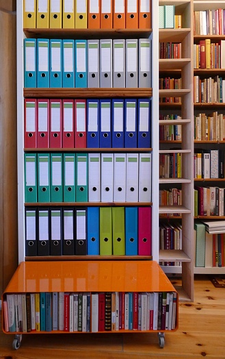 Colorful ring binders on a wooden shelf