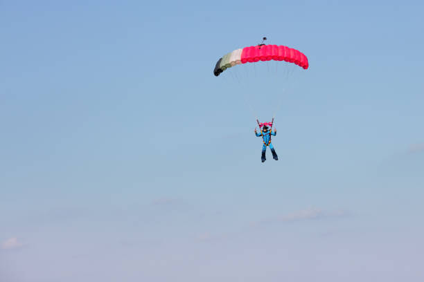 istock skydiver  on black and pink parachute on background clear blue sky 870493016