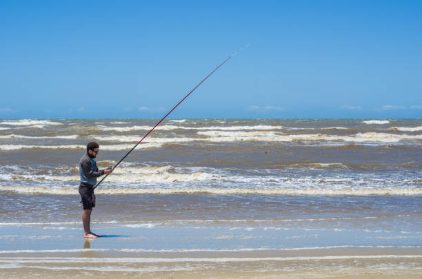 istock Young man fishing on beach 870495448