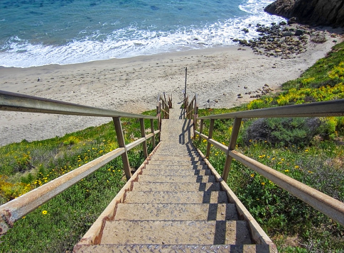 stairs descending to sand and surf at beach in Malibu, California