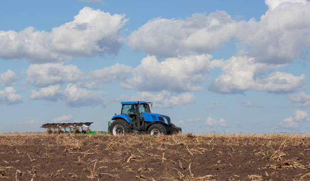 istock a large blue tractor, plowing field against the beautiful sky 870500456