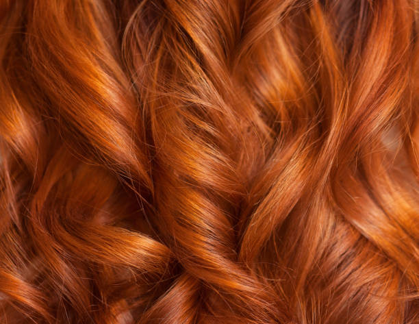 美しい、健康な長い、巻き毛、赤い髪をクローズ アップ。 ヘアアイロンでカールを作る。