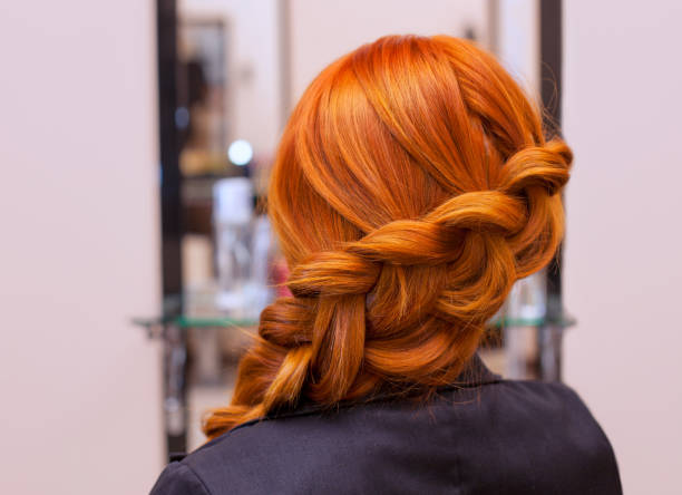 beautiful girl with long red hair, braided with a french braid, in a beauty salon - braided braids women long hair imagens e fotografias de stock