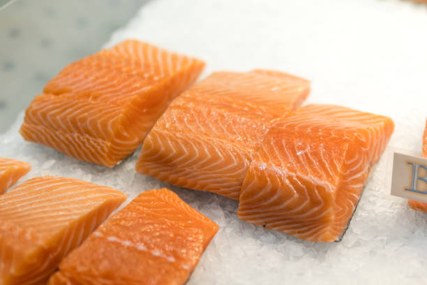 close up of salmon fillets spread over ice on a fishmonger's market stall in england - alaskan salmon imagens e fotografias de stock