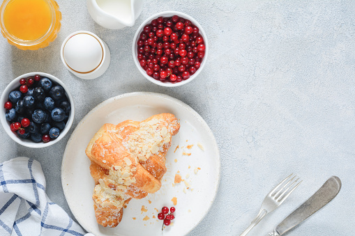 Fresh croissant, berries, honey and berries on table. Top view. Breakfast food with copy space for text