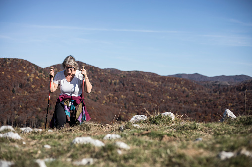 Senior woman on the walkway on Puy Pariou looking towards Puy de Dome in the Auvergne region of France. AdobeRGB colorspace.