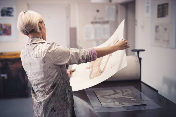 istock Assistant woman learning how to manually apply color on printed graphics 870565066