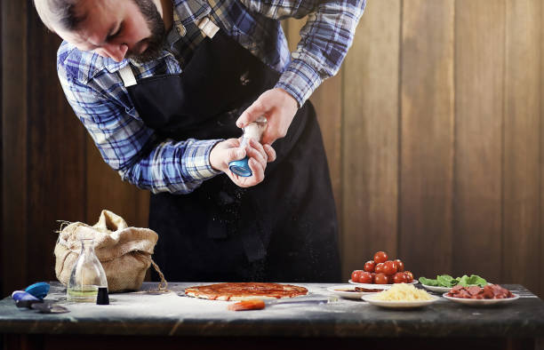 istock man in an apron preparing a pizza, knead the dough and puts ingr 870571622