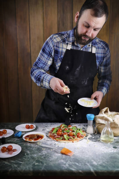 istock man preparing a pizza, knead the dough and puts ingredients 870572008