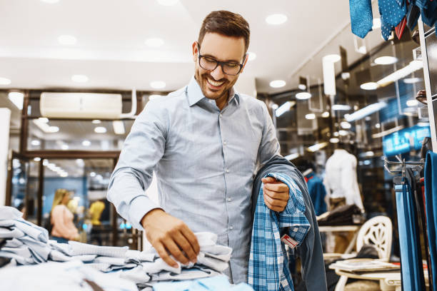 Man enjoyig shopping Portrait of handsome young man buying clothes in the store. shopping photos stock pictures, royalty-free photos & images