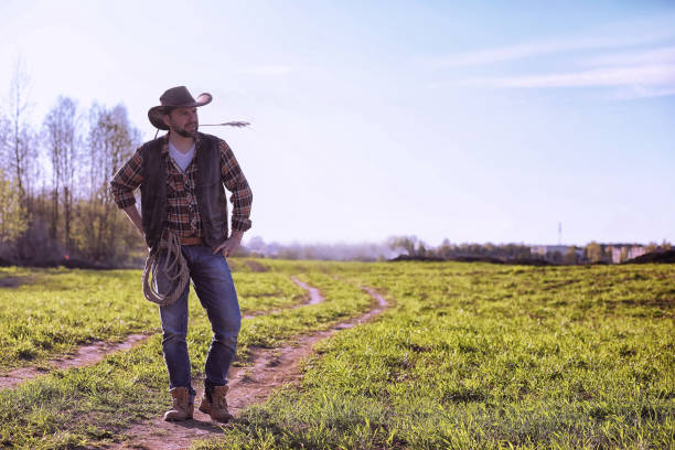 istock Cowboy standing in a field at sunset 870582438