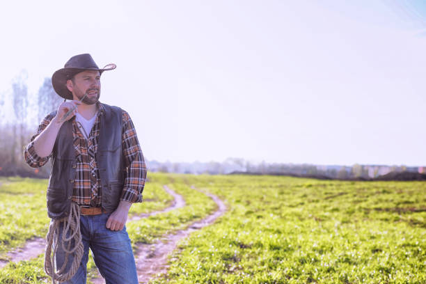 istock Cowboy standing in a field at sunset 870582454