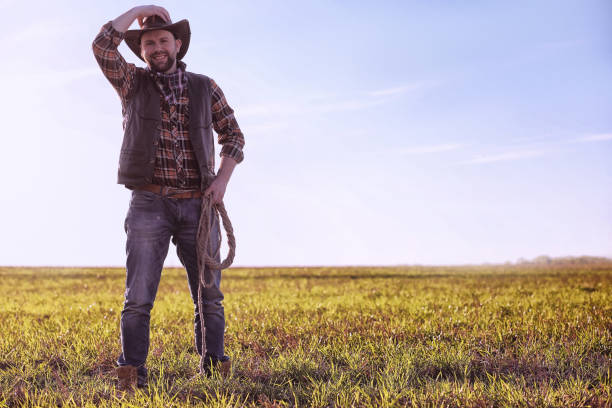 istock Cowboy standing in a field at sunset 870585074