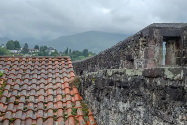 sight on red roof tiles and grey citywall in Saint Jean Pied de Port in France with Pyrenees  mountains in background
