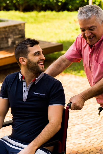 istock Dad helping his son sitting in his wheelchair 870599150