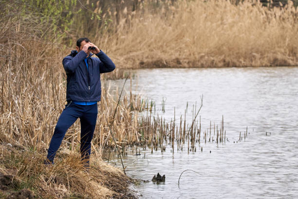 istock Man watching birds by the lake 870606380