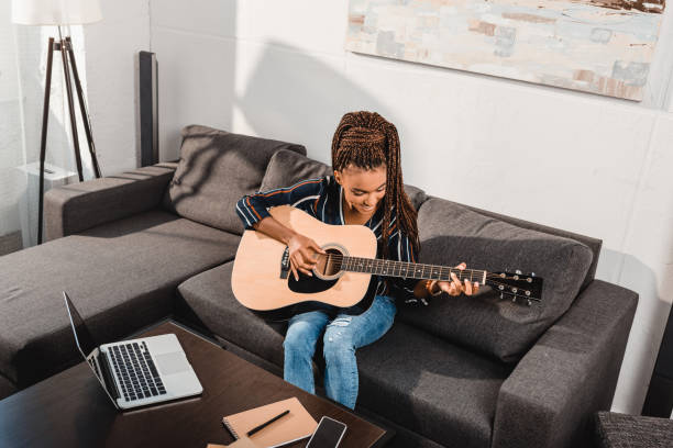 woman playing guitar on couch