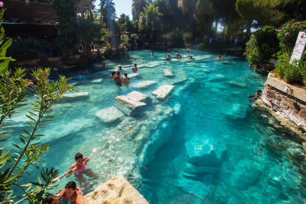 Pamukkale, Turkey - February 20, 2012: People are bathing in the natural spring pool also known as the Cleopatra's Pool in the ancient site of Hierapolis, Pamukkale in Denizli Region of Turkey.