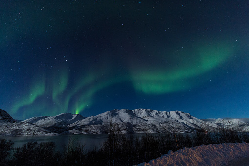 This picture was taken near Alta, Norway on a clear night. Green northern lights were visible above the mountains.
